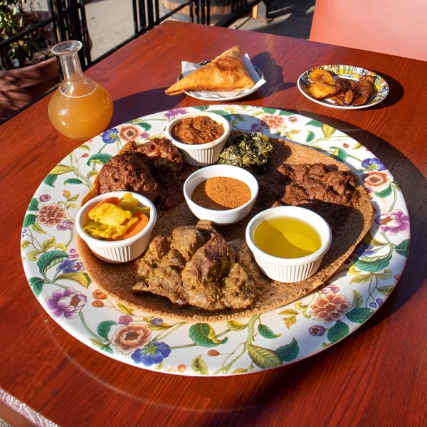 Rosalind's Ethiopian platter with injera, various stews, sauces, and sides, plus a drink and samosa.