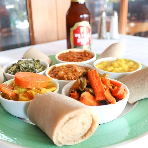 Rosalind's Ethiopian platter with various stews, vegetables, injera bread, and a beer bottle.